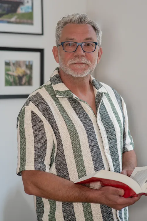 Thomas Selgert, Mitarbeiter bei Anwalt und Notar Illner in Bochum, hält ein geöffnetes Buch in den Händen und schaut den Besucher an.